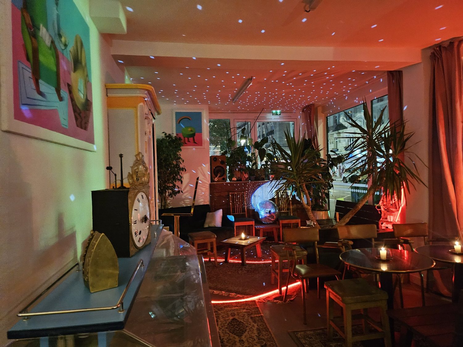 La salle le soir, bougies sur les tables, ruban rouge au sol et étoiles de la boule à facettes au plafond